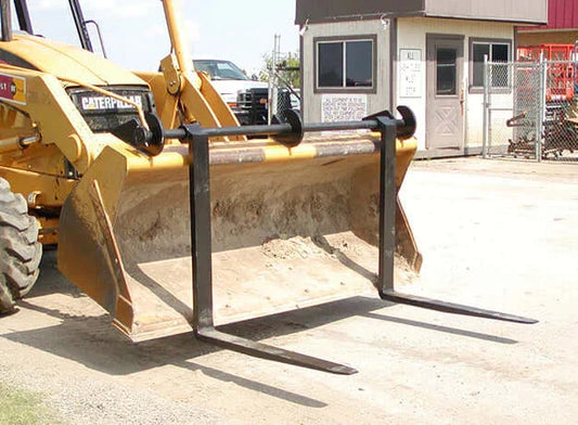 Yellow Caterpillar machinery with FLECO Bucket Forks attached, designed to fit Small Loaders and Backhoes. The forks are adjustable and made of fully forged tines, situated in an outdoor construction environment.