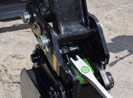 Close-up of Geith Mechanical Quick Coupler's connectors and lever, displaying Geith logo, set against a gravel backdrop.