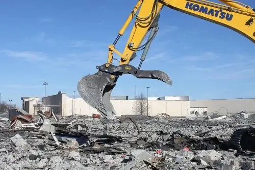 Komatsu excavator with Geith thumb grabbing debris in rubble.